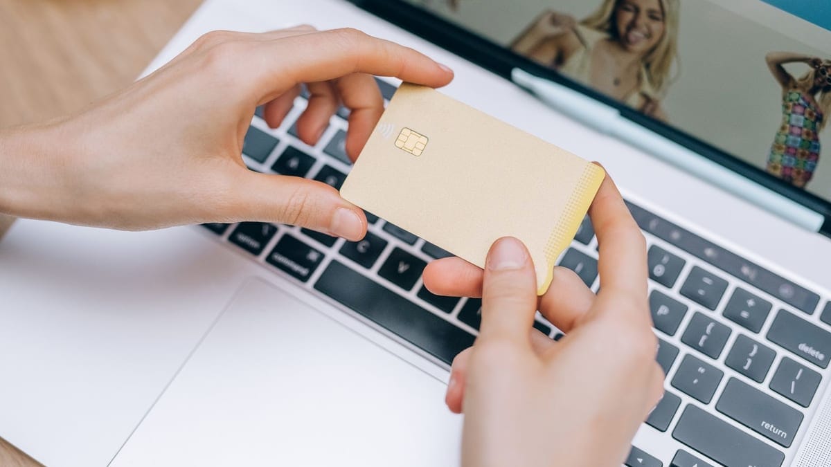 Close-up of hands holding credit card for online shopping on a laptop. Perfect for e-commerce and finance visuals.