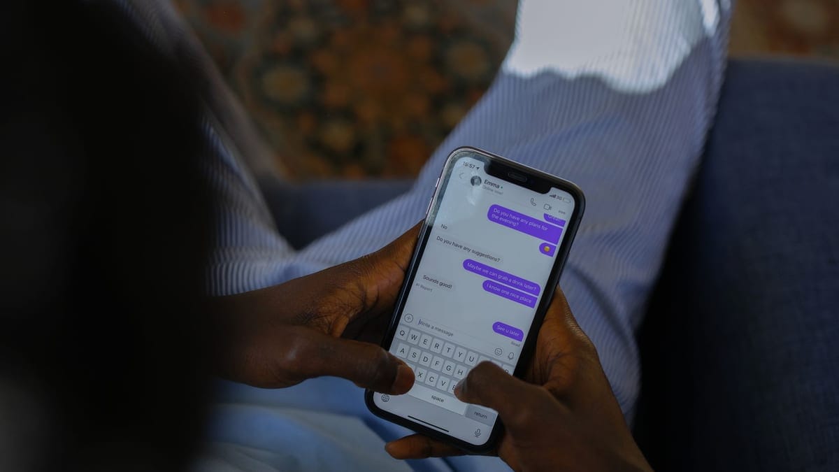 Close-up of hands holding a smartphone, typing a message on a touch screen indoors.